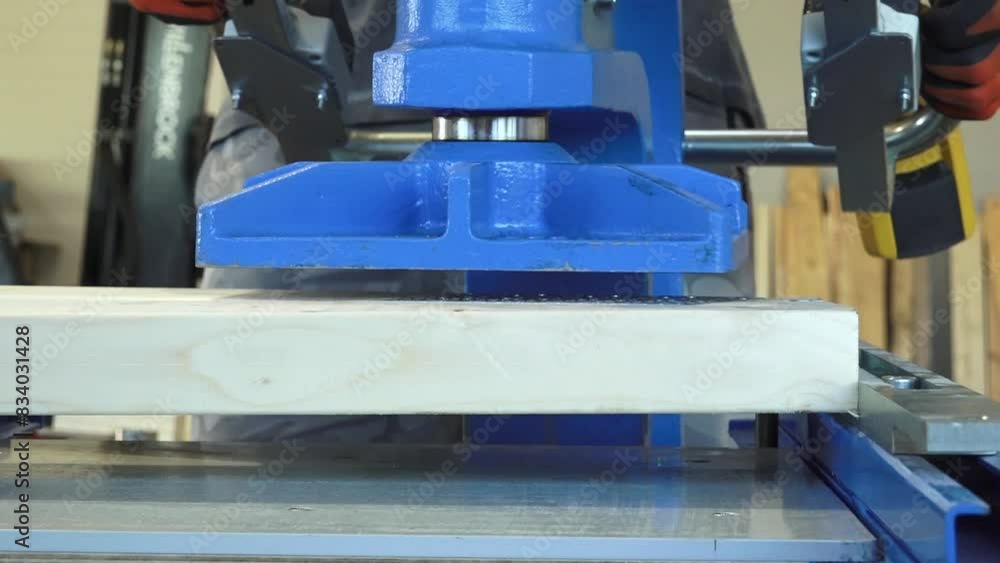 Balvi, Latvia - May 25, 2024 - Machine pressing metal plates into a wooden plank, demonstrating an industrial joinery process with precision. Balvi, Latvia - May 25, 2024 - Machine pressing metal plates into a wooden plank, demonstrating an industrial joinery process with precision.