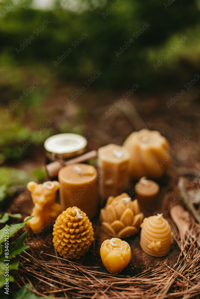 Handmade candles from natural beeswax in the shape of bear, pine cone and others, jars of honey. Hobby. Beekeeping. Artistic photo of beekeeping products against the backdrop of nature, forest Handmade candles from natural beeswax in the shape of bear, pine cone and others, jars of honey. Hobby. Beekeeping. Artistic photo of beekeeping products against the backdrop of nature, forest