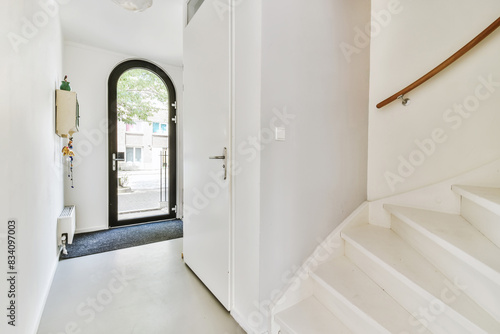 Bright entryway with open door and white staircase