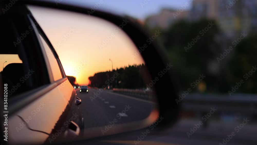 View in the side rear view mirror of a car driving a red car on a highway View in the side rear view mirror of a car driving a red car on a highway