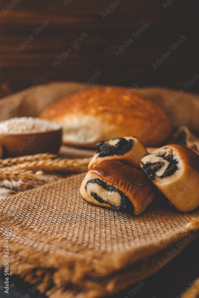 Fototapeta premium Wooden board with tasty cut poppy seed bun on table
