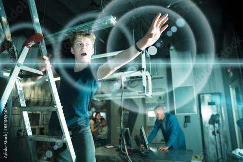 Teenage boy, pointing at something from a stepladder, tries to find a solution to a puzzle in the quest room photo