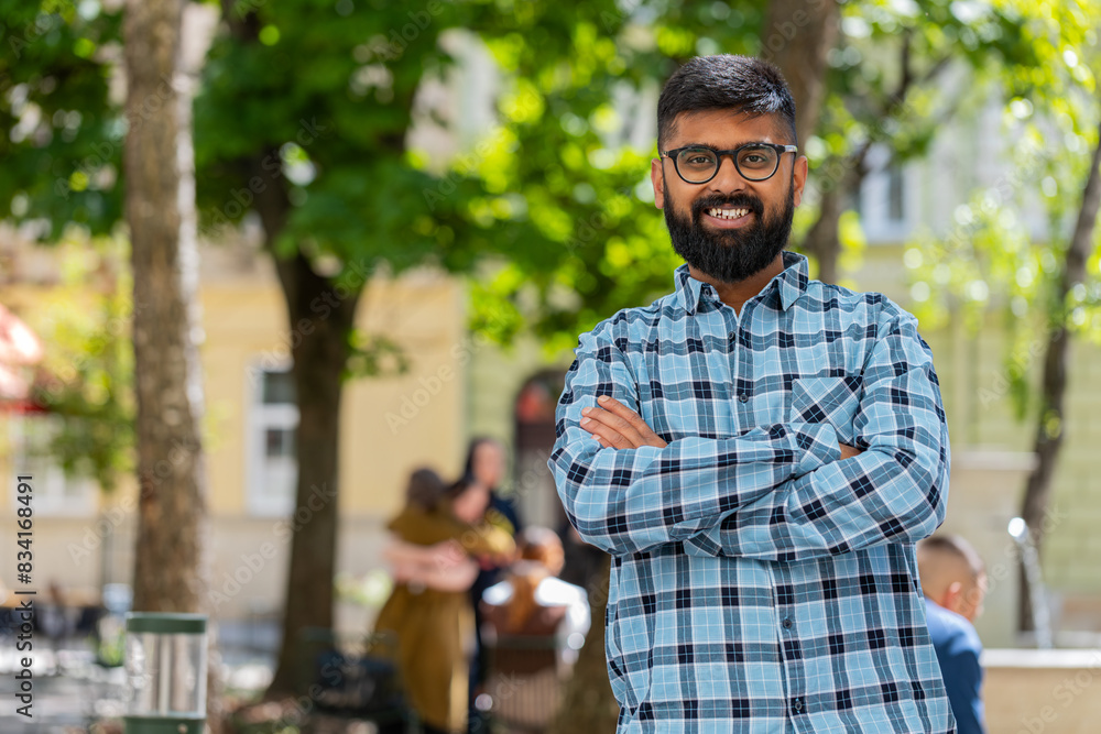 Indian bearded man tourist walking on urban city street outdoors in summer daytime. Hispanic guy traveler smiling having positive good mood enjoying vacation holidays. Town lifestyles. Horizontal Indian bearded man tourist walking on urban city street outdoors in summer daytime. Hispanic guy traveler smiling having positive good mood enjoying vacation holidays. Town lifestyles. Horizontal