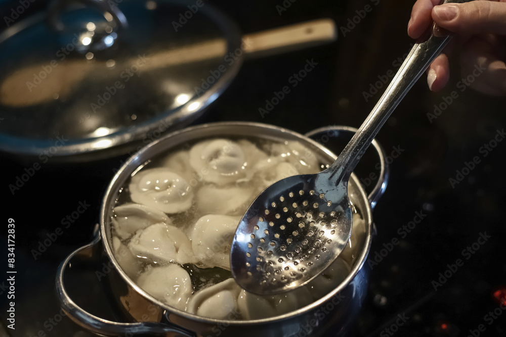 Making dinner at home. Cooking pelmeni in saucepan with boiling water in domestic kitchen. Photo with selective focus Making dinner at home. Cooking pelmeni in saucepan with boiling water in domestic kitchen. Photo with selective focus