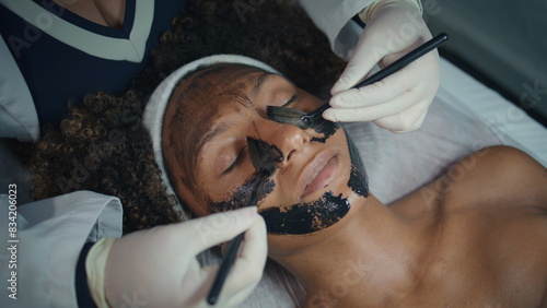 Hands applying face mask in spa salon closeup. Relaxed patient visit cosmetician