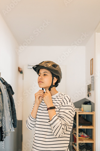 A teenage girl putting on her bike helmet getting ready to go out, morning routine