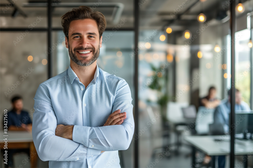 Portrait of cheerful businessman with arms folded standing in conference room. Happy young business man in shirt looking at camera. Portrait of a smiling businessman in modern office Portrait of cheerful businessman with arms folded standing in conference room. Happy young business man in shirt looking at camera. Portrait of a smiling businessman in modern office