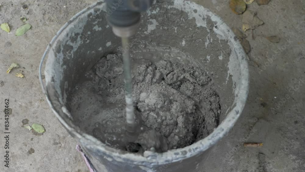 To tile wall, mix plaster adhesive in black bucket. Use electric mixer to ensure smooth even consistency. This preparation makes the tiling process easier and more efficient To tile wall, mix plaster adhesive in black bucket. Use electric mixer to ensure smooth even consistency. This preparation makes the tiling process easier and more efficient