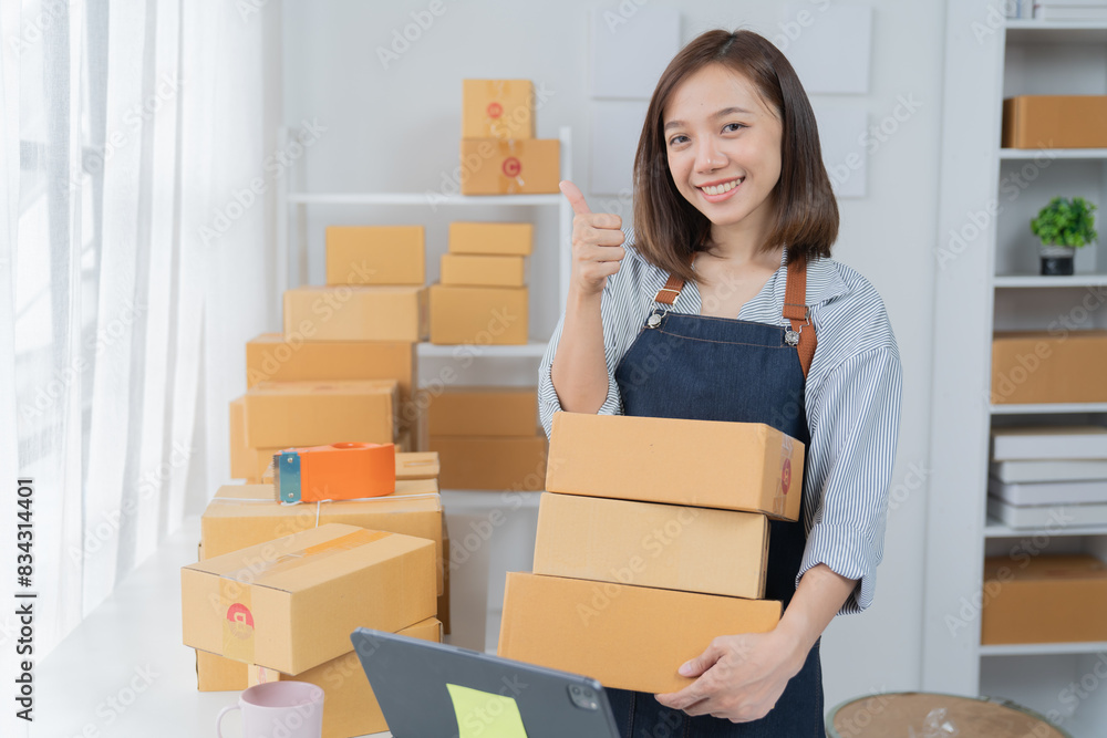 Delivery business. happy modern female checking order with laptop and using smartphone applications in the warehouse Delivery business. happy modern female checking order with laptop and using smartphone applications in the warehouse