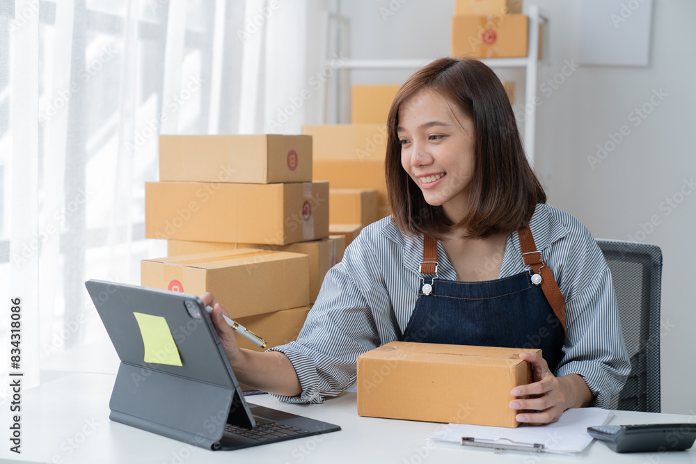 Delivery business. happy modern female checking order with laptop and using smartphone applications in the warehouse Delivery business. happy modern female checking order with laptop and using smartphone applications in the warehouse