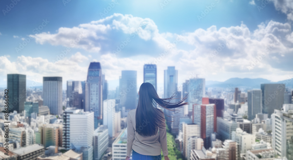 Naklejka premium 日本の街・都市・朝日を受けたオフィスビル群を前に佇み風を受けて髪をなびかせる会社員の女性の出勤 ビジネス・はじまり・決意・目標・挑戦のイメージ