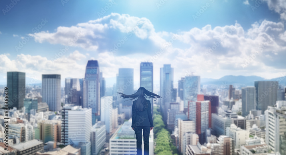 Fototapeta 日本の街・都市・朝日を受けたオフィスビル群を前に佇み風を受けて髪をなびかせる会社員の女性の出勤　ビジネス・はじまり・決意・目標・挑戦のイメージ