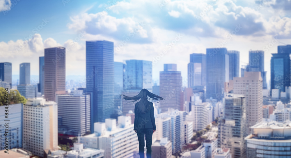 Fototapeta 日本の街・都市・朝日を受けたオフィスビル群を前に佇み風を受けて髪をなびかせる会社員の女性の出勤　ビジネス・はじまり・決意・目標・挑戦のイメージ