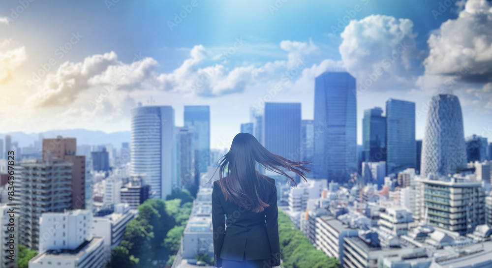 Obraz premium 日本の街・都市・朝日を受けたオフィスビル群を前に佇み風を受けて髪をなびかせる会社員の女性の出勤 就職・ビジネス・はじまり・決意・目標・挑戦のイメージ