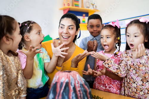 Teacher and group of children learning about volcanos at science kindergarten project. Multiracial kids studying at elementary school. Education concept