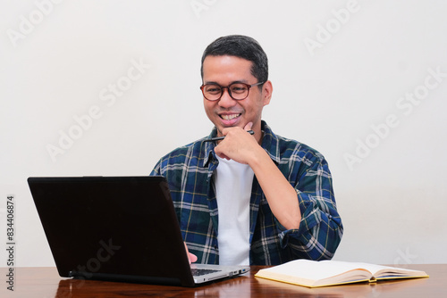 A man on workingplace showing happy expression when looking to the laptop photo