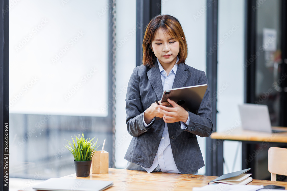 Young happy business asian woman using digital tablet while work in the office. Copy space. Young happy business asian woman using digital tablet while work in the office. Copy space.