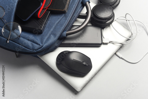 Laptop with Modern gadgets and accessories for work and study in Backpack on white background.