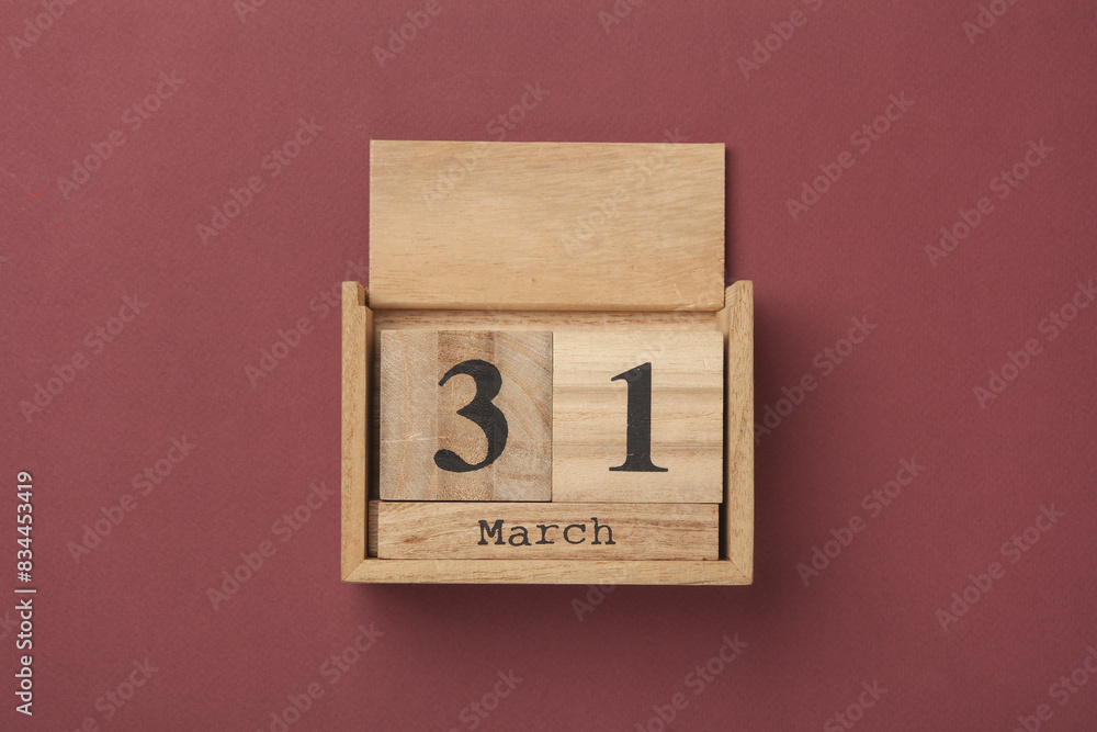 Wooden block calendar with date March 31 on burgundy backround. Top view. Flat lay Wooden block calendar with date March 31 on burgundy backround. Top view. Flat lay