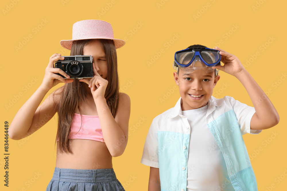 Cute little children with snorkeling mask and camera taking picture on yellow background Cute little children with snorkeling mask and camera taking picture on yellow background