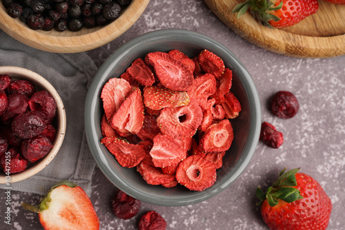 Bowl with freeze-dried strawberry and cherries on grey background photo