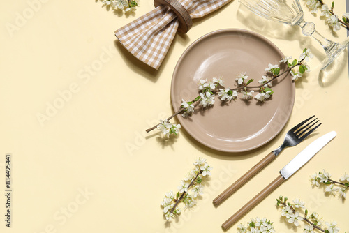Beautiful table setting with blossoming branches on yellow background