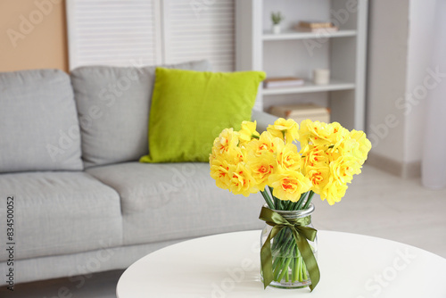 Vase with daffodil flowers on coffee table in living room © Pixel-Shot