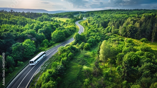 A tranquil highway curves through a vibrant green forest, showcasing a white travel bus on its route. The scene, captured in wide-angle, 70mm focus, emphasizes the peaceful journey and vivid hues.