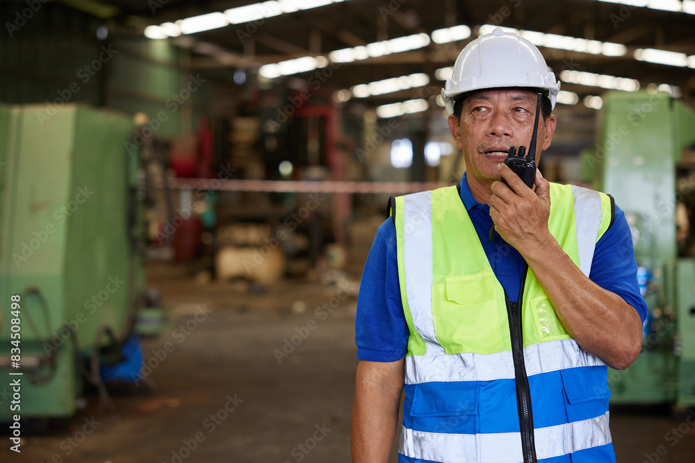 senior worker talking on walkie talkie in the factory senior worker talking on walkie talkie in the factory
