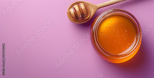 A honey dipper resting on a puddle of honey next to a bowl on a purple wooden surface, accented by small flowers, creating a sweet and aromatic scene. photo