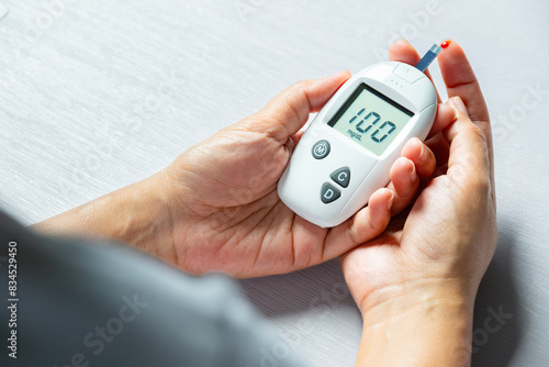 Woman's hands checking diabetes and hyperglycemia with digital blood sugar meter. Healthcare and medical concept 