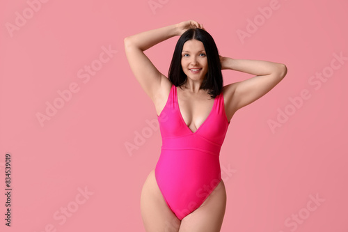 Beautiful young woman in stylish swimsuit on pink background