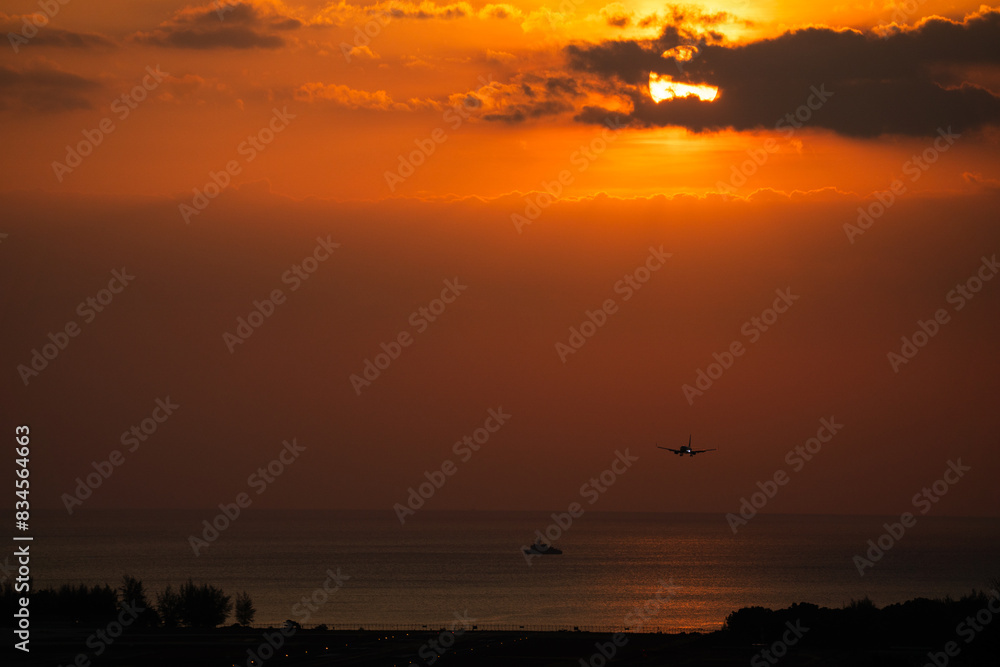 Back view silhouette of airplane landing at the airport at sunny orange and purple sunset. Runway Back view silhouette of airplane landing at the airport at sunny orange and purple sunset. Runway