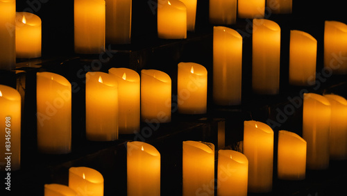Foto A multitude of lit cylindrical candles arranged on shelves and emitting a warm glow