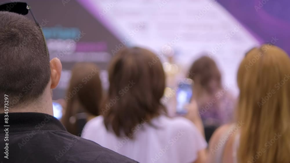 A crowd is gathered at an event, focusing on a persons head from the back with the image blurred A crowd is gathered at an event, focusing on a persons head from the back with the image blurred