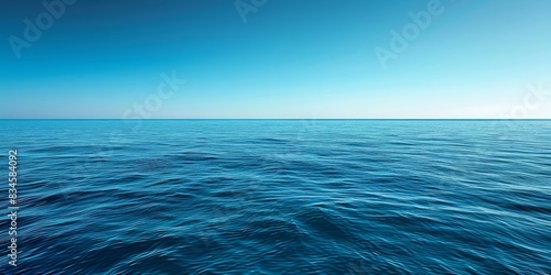 A tranquil sea stretching into the horizon beneath a cloudless summer blue sky