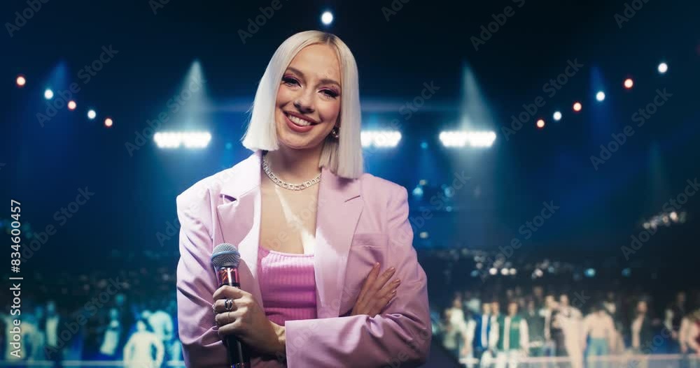 Portrait of a Beautiful Female Artist Standing on Stage at a Concert, Posing and Looking at Camera. Young Empowering Singer Standing with Her Arms Crossed, Smiling and Holding a Microphone Portrait of a Beautiful Female Artist Standing on Stage at a Concert, Posing and Looking at Camera. Young Empowering Singer Standing with Her Arms Crossed, Smiling and Holding a Microphone