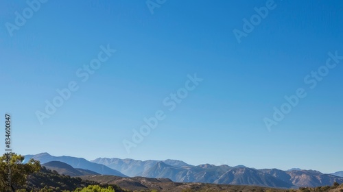 A serene mountain landscape with clear blue skies, offering a large area of copy space in the sky. photo