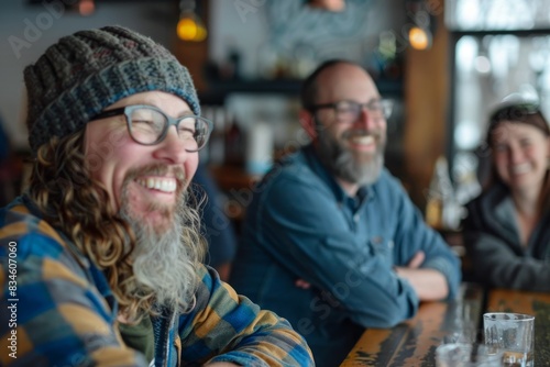 Happy hipster man with long curly hair and beard in glasses sitting in a pub