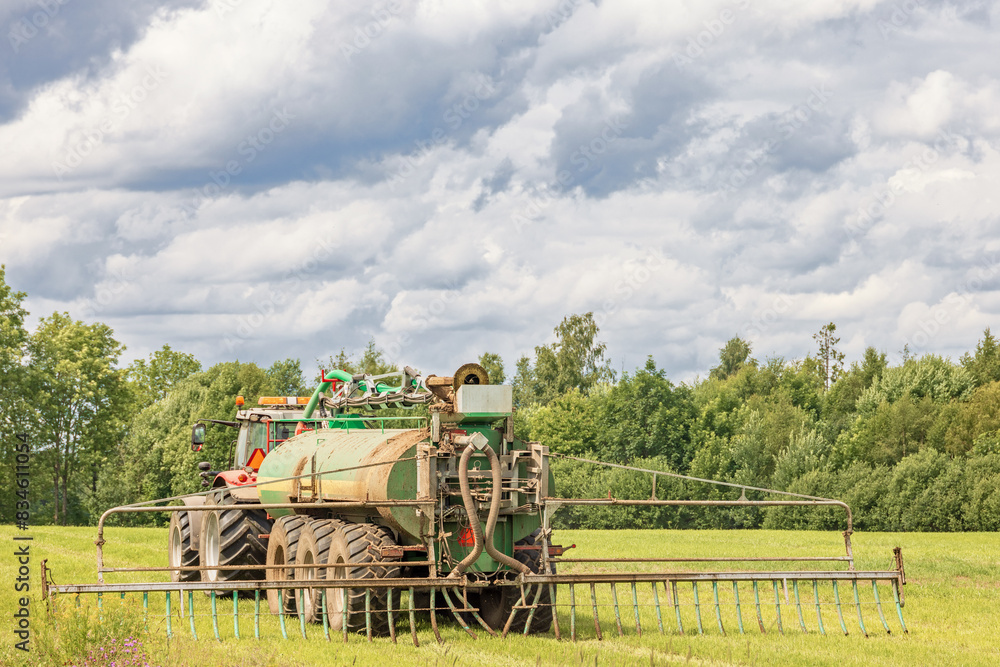 Tractor driving on a field and fertilizing a sunny summer day Tractor driving on a field and fertilizing a sunny summer day