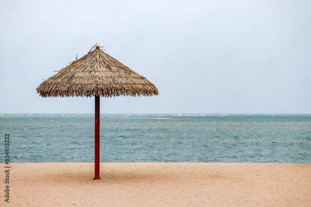 Straw umbrella on the beach in Doha on a cloudy day Straw umbrella on the beach in Doha on a cloudy day
