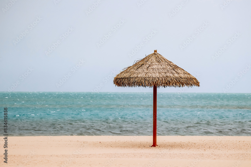 Straw umbrella on the beach in Doha on a cloudy day Straw umbrella on the beach in Doha on a cloudy day