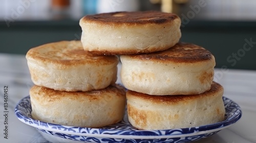  A stack of pancakes on a blue-and-white plate, resting on a white countertop Nearby, a blue-and-white bowl with a blue design