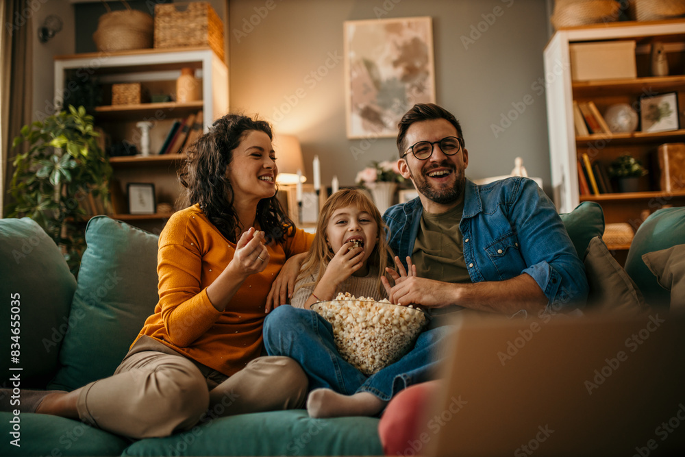 © La Famiglia - Smiling Caucasian family sitting on the couch and watching a comedy on the TV