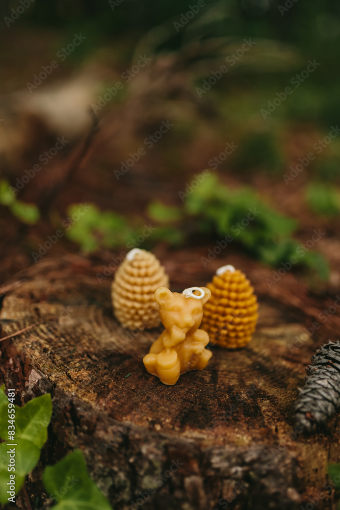 Handmade candles from natural beeswax in the shape of bear, pine cones on an old stump in the forest. Hobby. Artistic photo of beekeeping products against the backdrop of nature Handmade candles from natural beeswax in the shape of bear, pine cones on an old stump in the forest. Hobby. Artistic photo of beekeeping products against the backdrop of nature