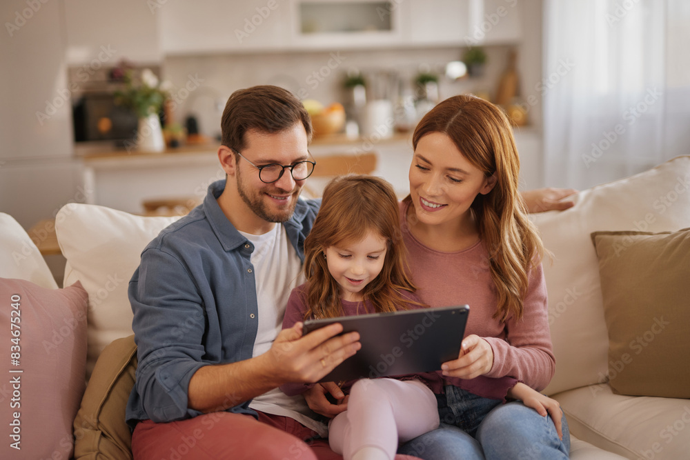 Curious little girl using the tablet with her parents in the living room Curious little girl using the tablet with her parents in the living room