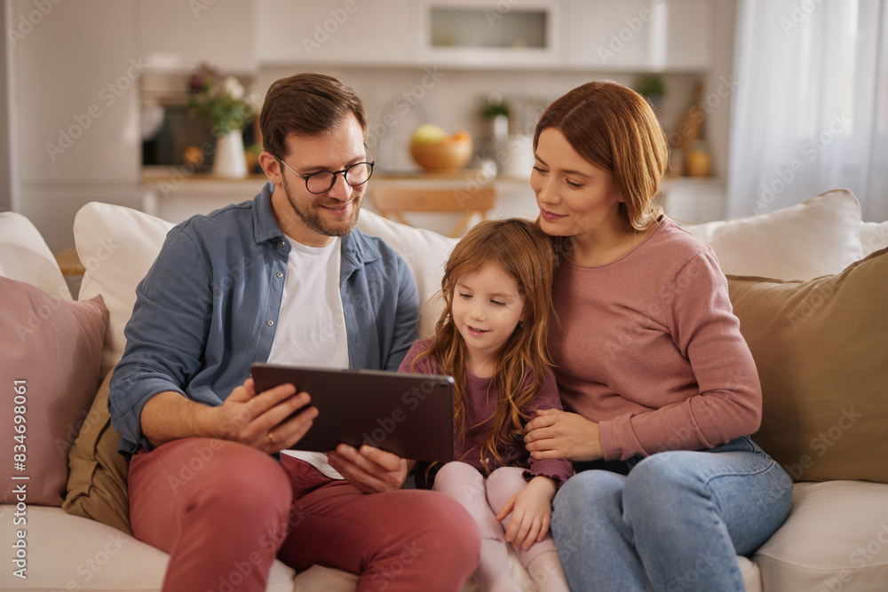 Curious little girl using the tablet with her parents in the living room Curious little girl using the tablet with her parents in the living room