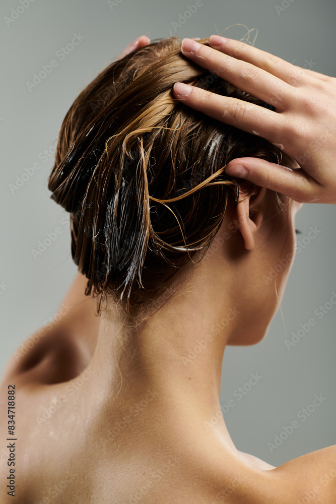 Naklejka premium Young woman demonstrates hair care routine with wet hair.