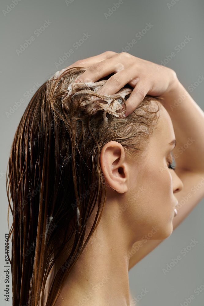 Naklejka premium Alluring woman applying hair care product and washing hair.