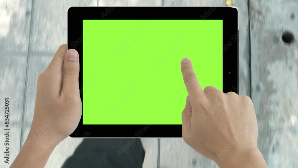 A person is holding a tablet with a green screen. The tablet is not displaying any content, but the person is holding it up to the light. Concept of anticipation or curiosity A person is holding a tablet with a green screen. The tablet is not displaying any content, but the person is holding it up to the light. Concept of anticipation or curiosity
